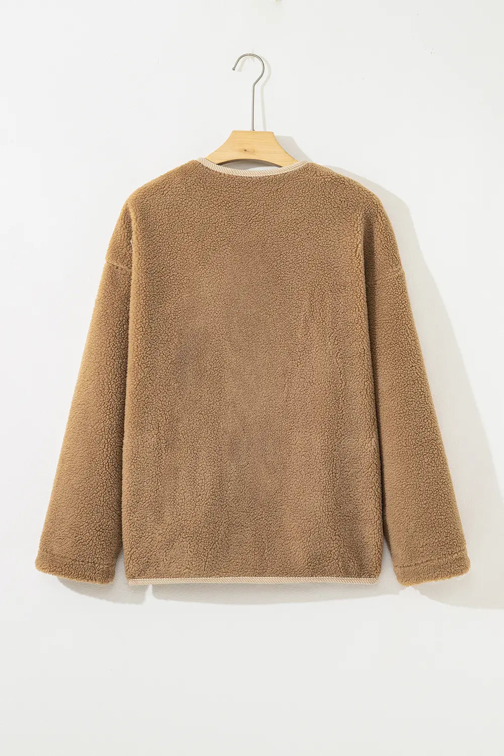 Brown textured sweater on a hanger against a white background