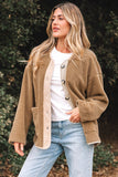 Woman wearing a brown teddy coat over a white shirt and blue jeans outdoors.