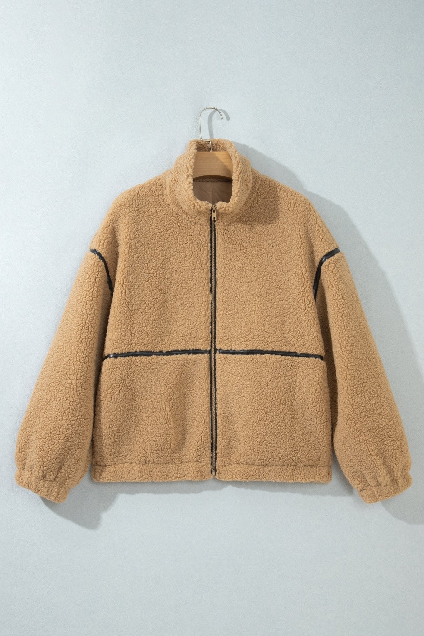 Tan sherpa fleece zip-up jacket with black contrast stitching on hanger.