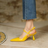 Yellow high-heeled shoes worn with blue jeans on a neutral background