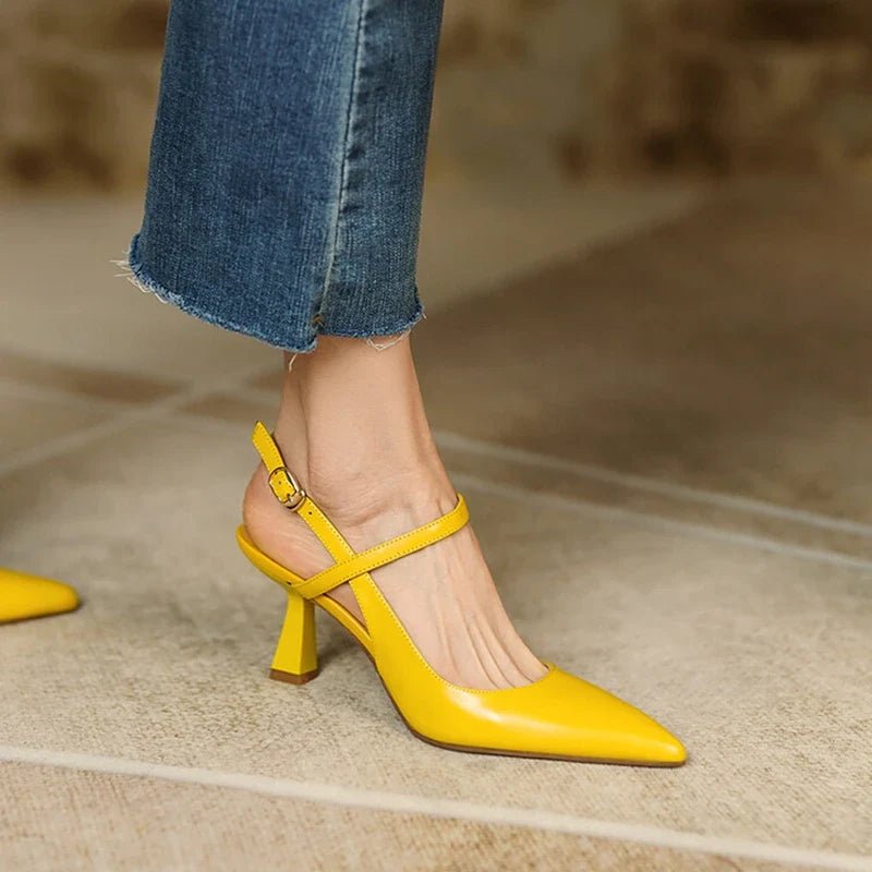Yellow high-heeled shoes worn with blue jeans on a neutral background
