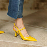 Yellow high-heeled shoes worn with blue jeans on a neutral background