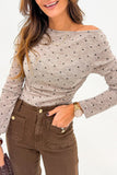 Woman wearing a polka dot top and brown pants with a neutral background