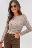 Woman wearing a polka dot long-sleeve top and brown pants against a white background