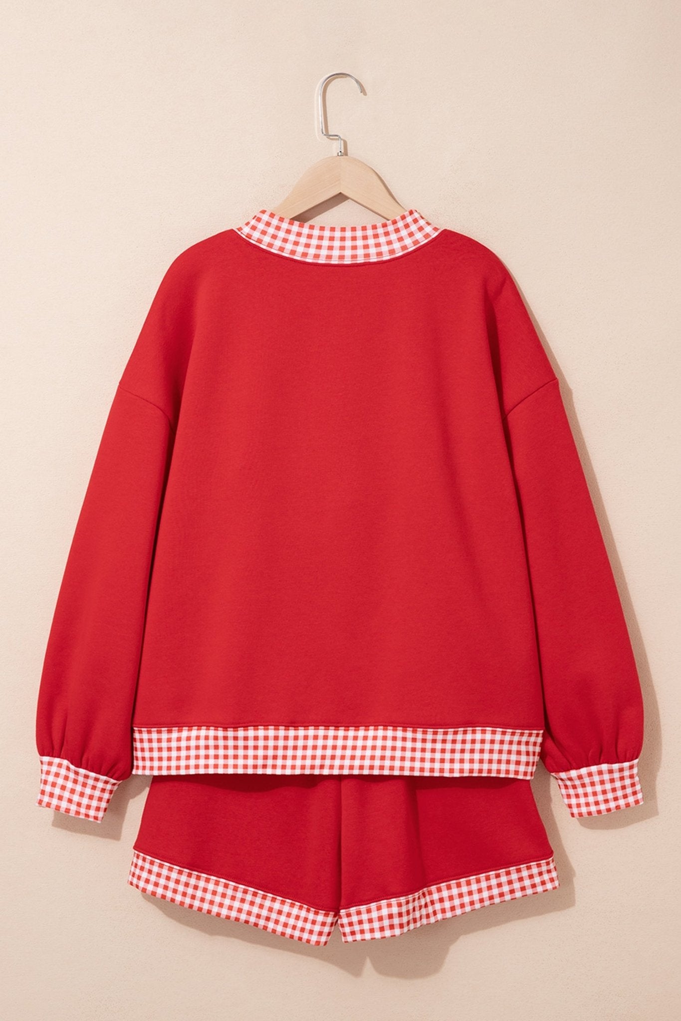 Red two-piece lounge set with sweatshirt and matching shorts, featuring red-white gingham trim.