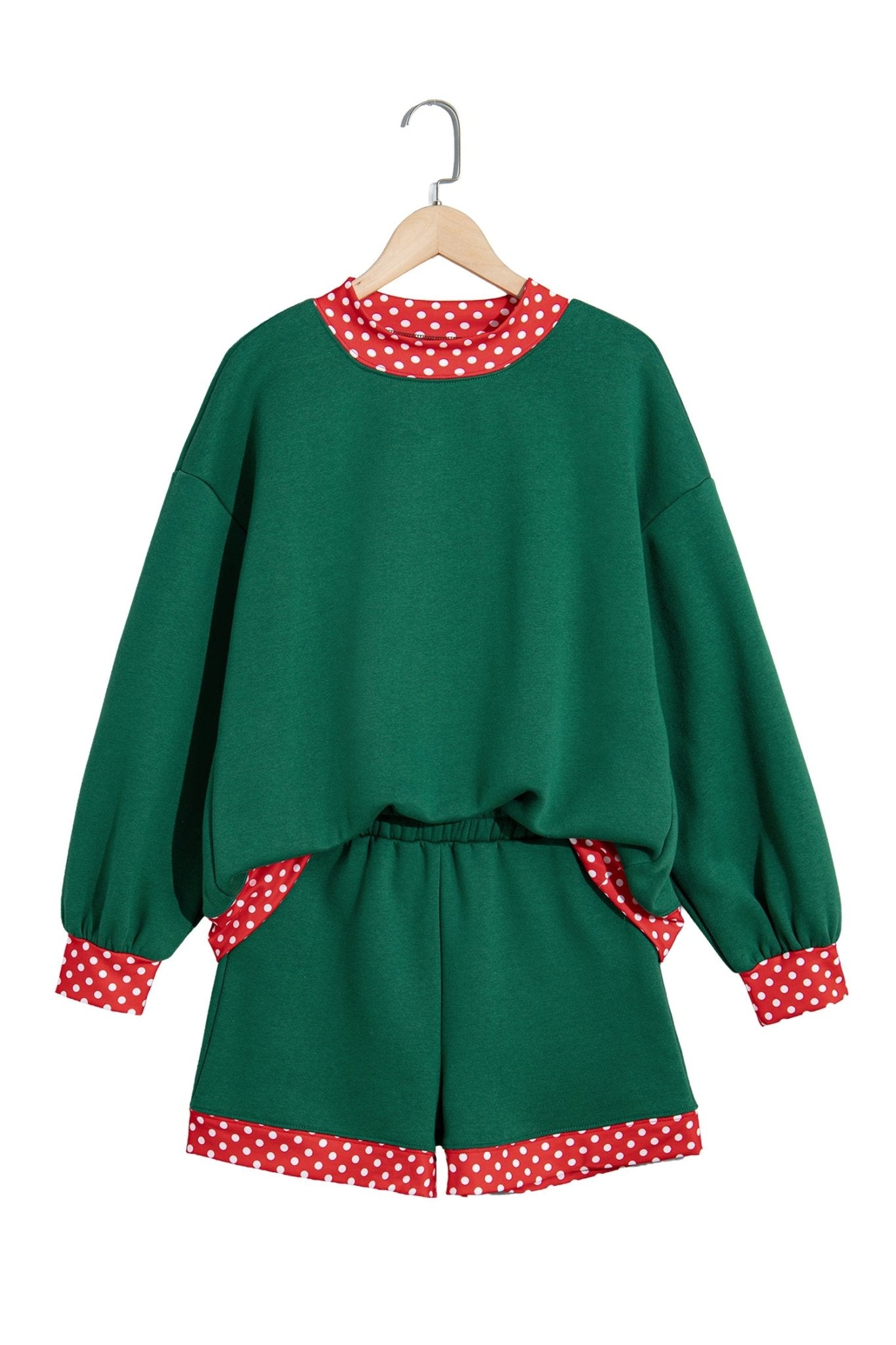 Green two-piece lounge set with sweatshirt and shorts, featuring red-white polka-dot trim, hanging on a wooden hanger.