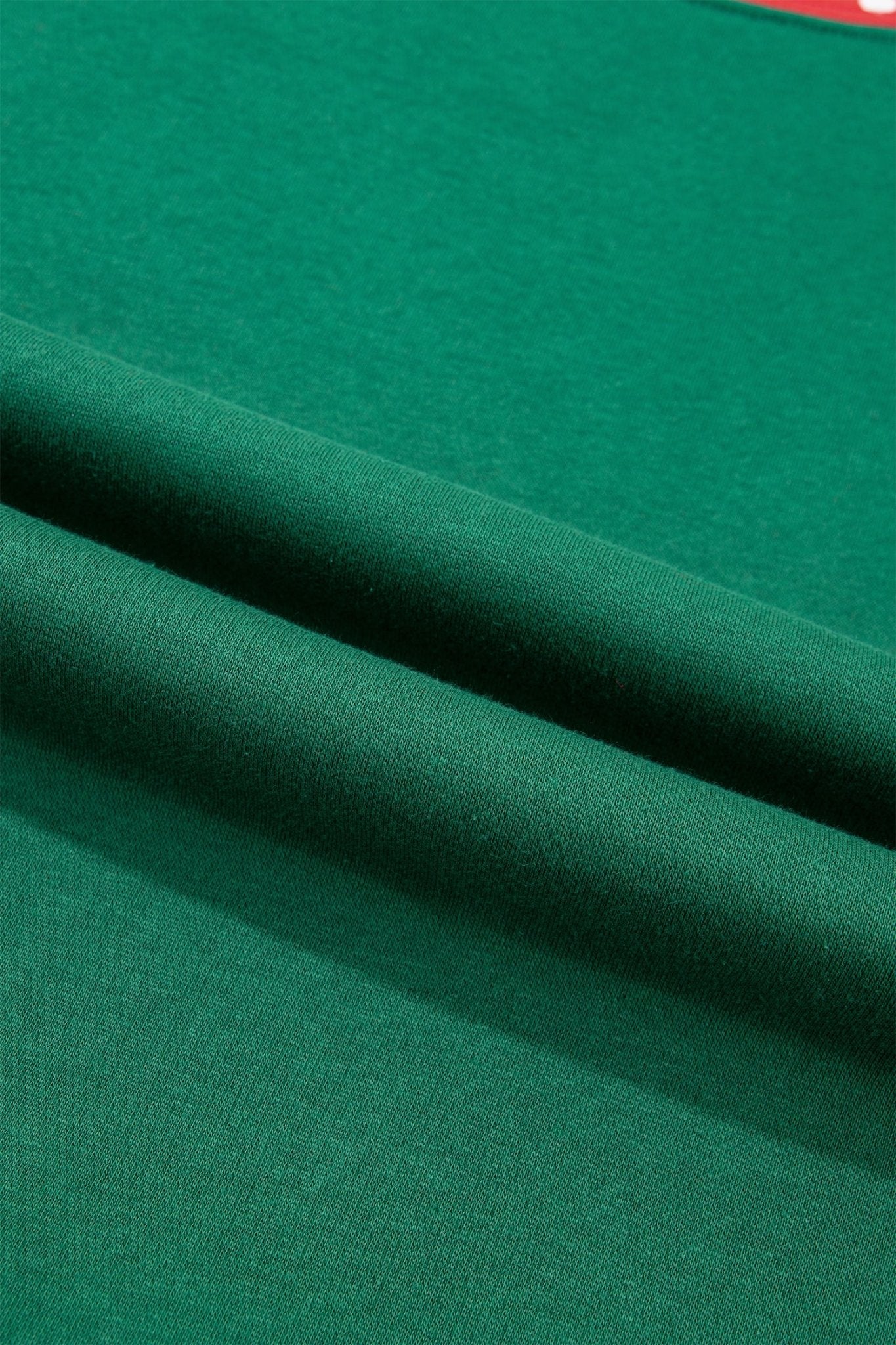 A close-up of dark green fabric with soft folds and a smooth texture.