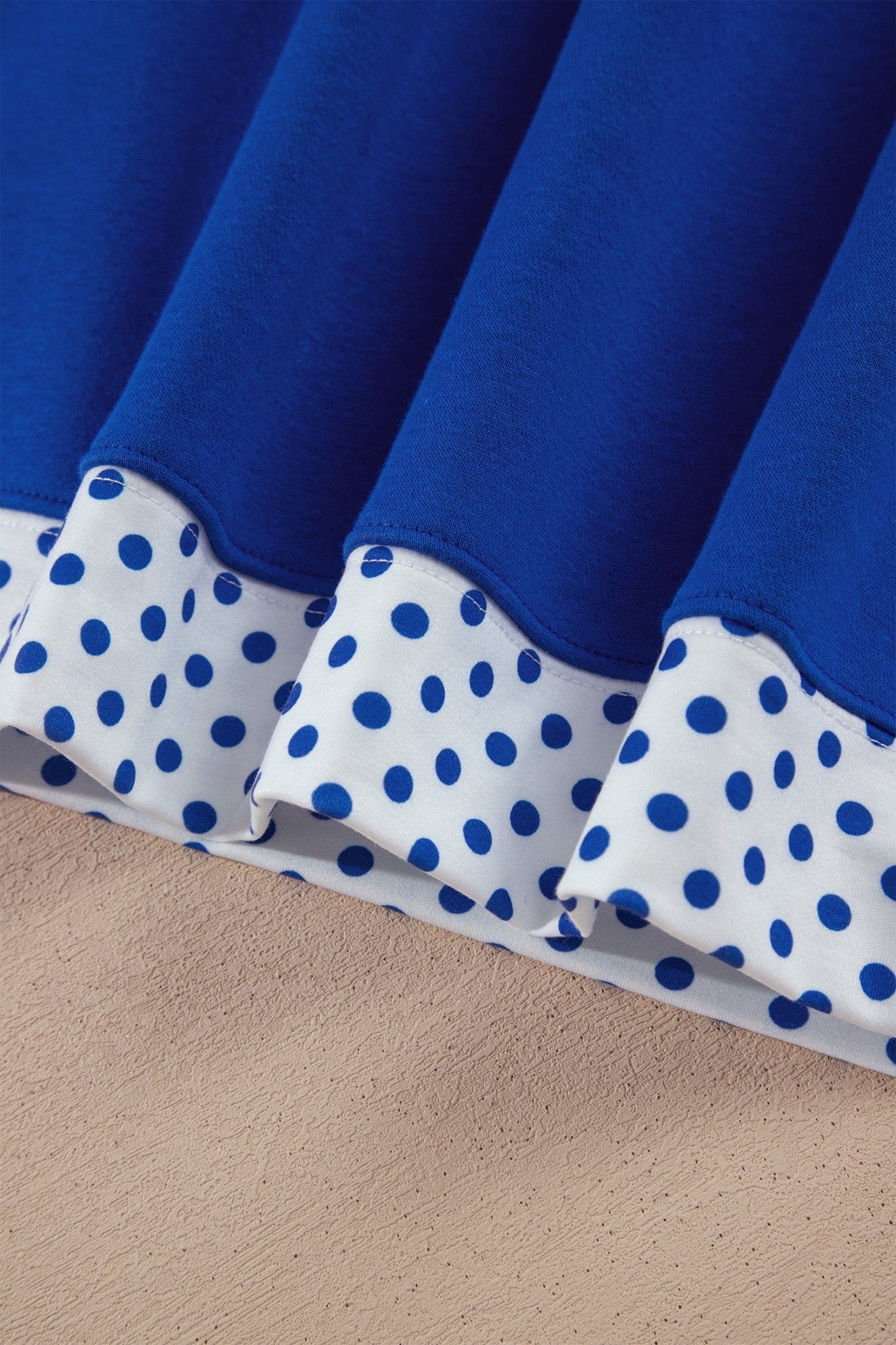 Close-up of pleated fabric with royal blue top and white lower band featuring blue polka dots.