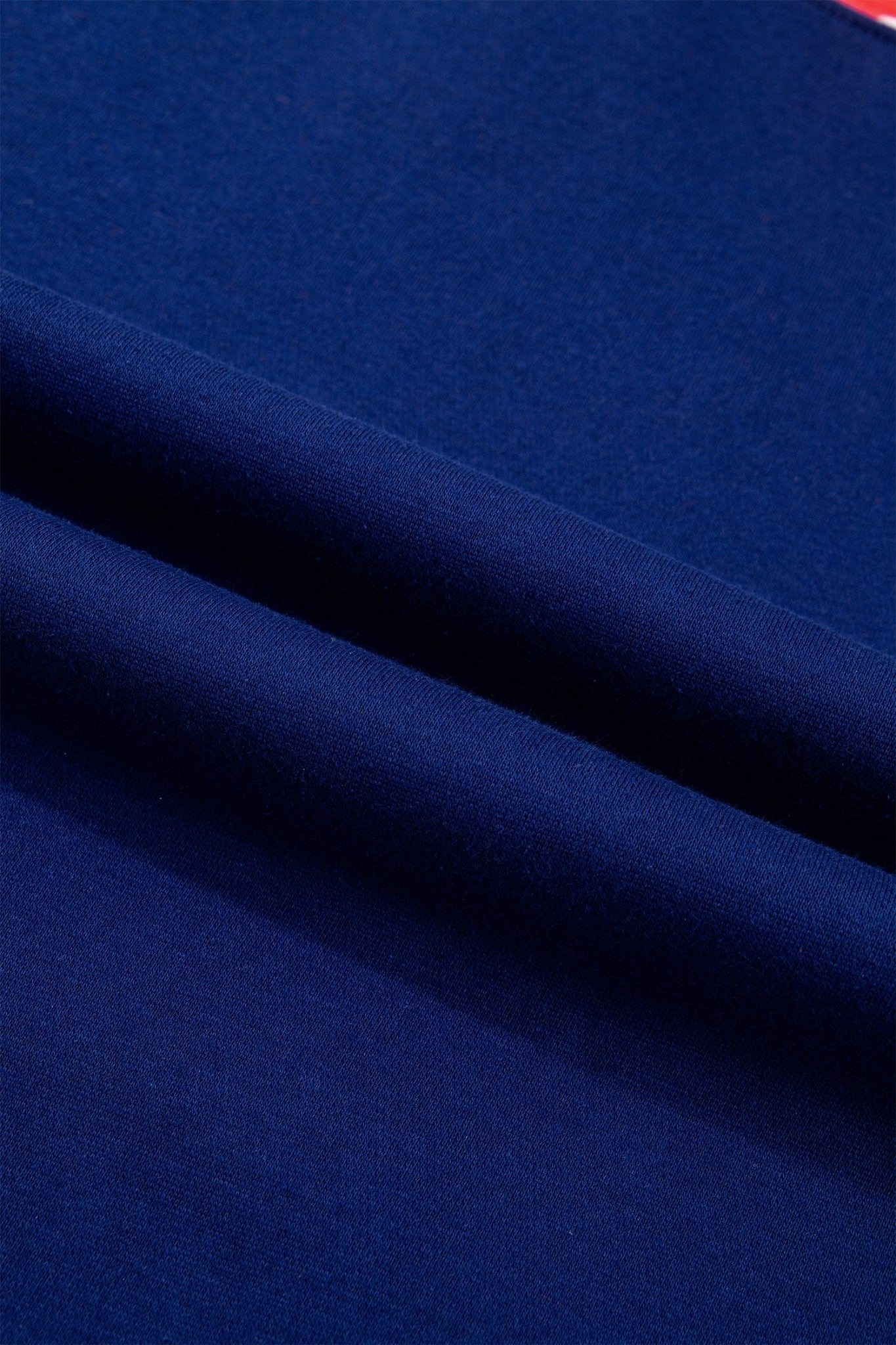 A close-up of dark navy blue fabric with soft diagonal folds showing its texture and color.