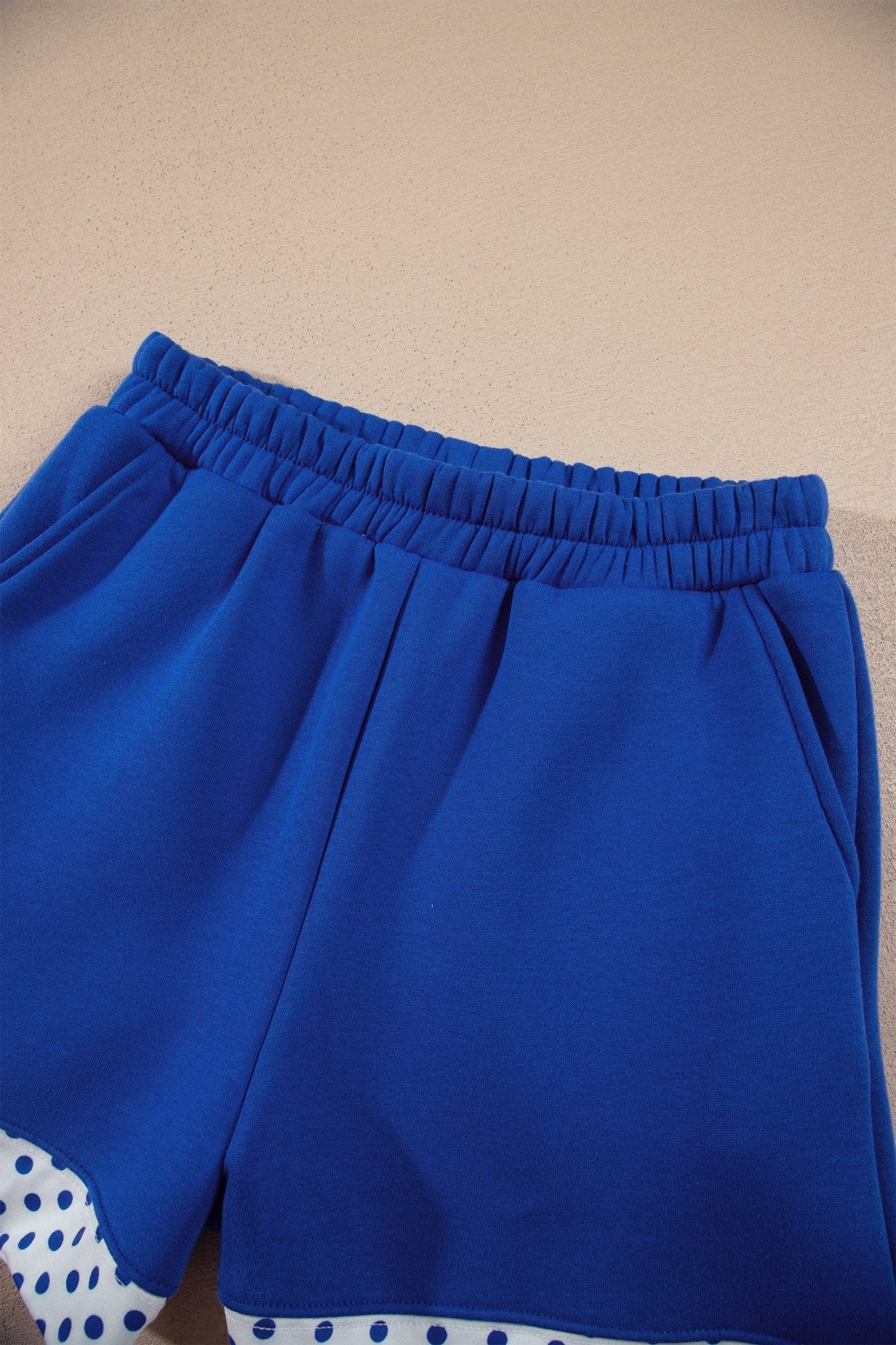 Royal blue athletic shorts with elastic waistband and white-blue polka-dot trim along the hem.