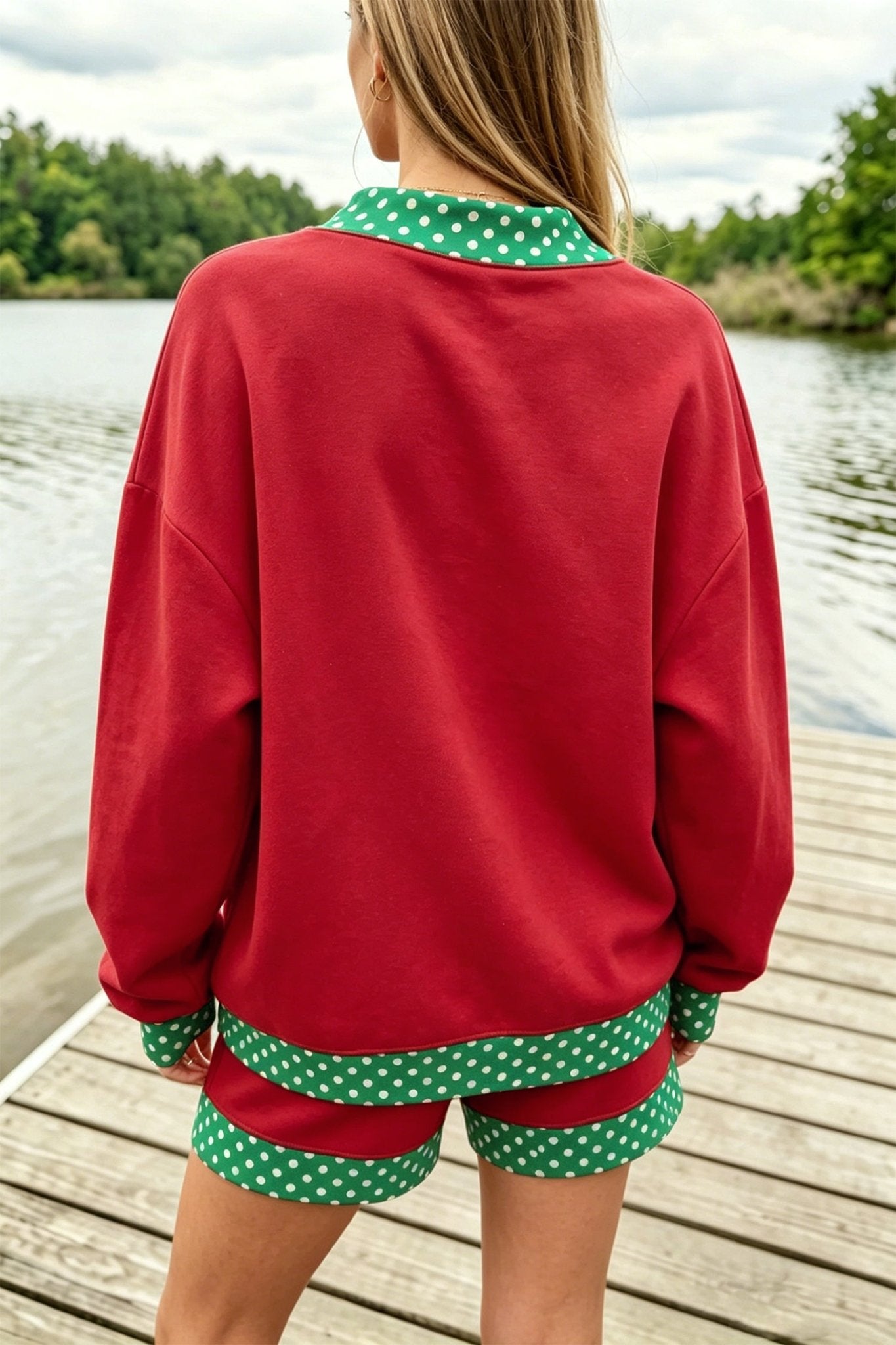 Woman viewed from behind wearing red top and matching shorts with green-white polka-dot trim by a lake.