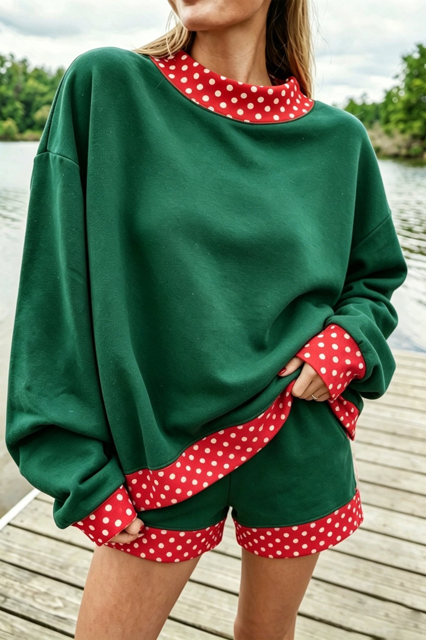Woman wearing green sweatshirt and matching shorts with red-white polka-dot trim on a wooden dock.