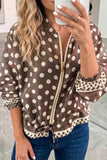 Woman in brown and beige polka dot zip-up jacket with ruffled trim and blue jeans, mirror selfie.
