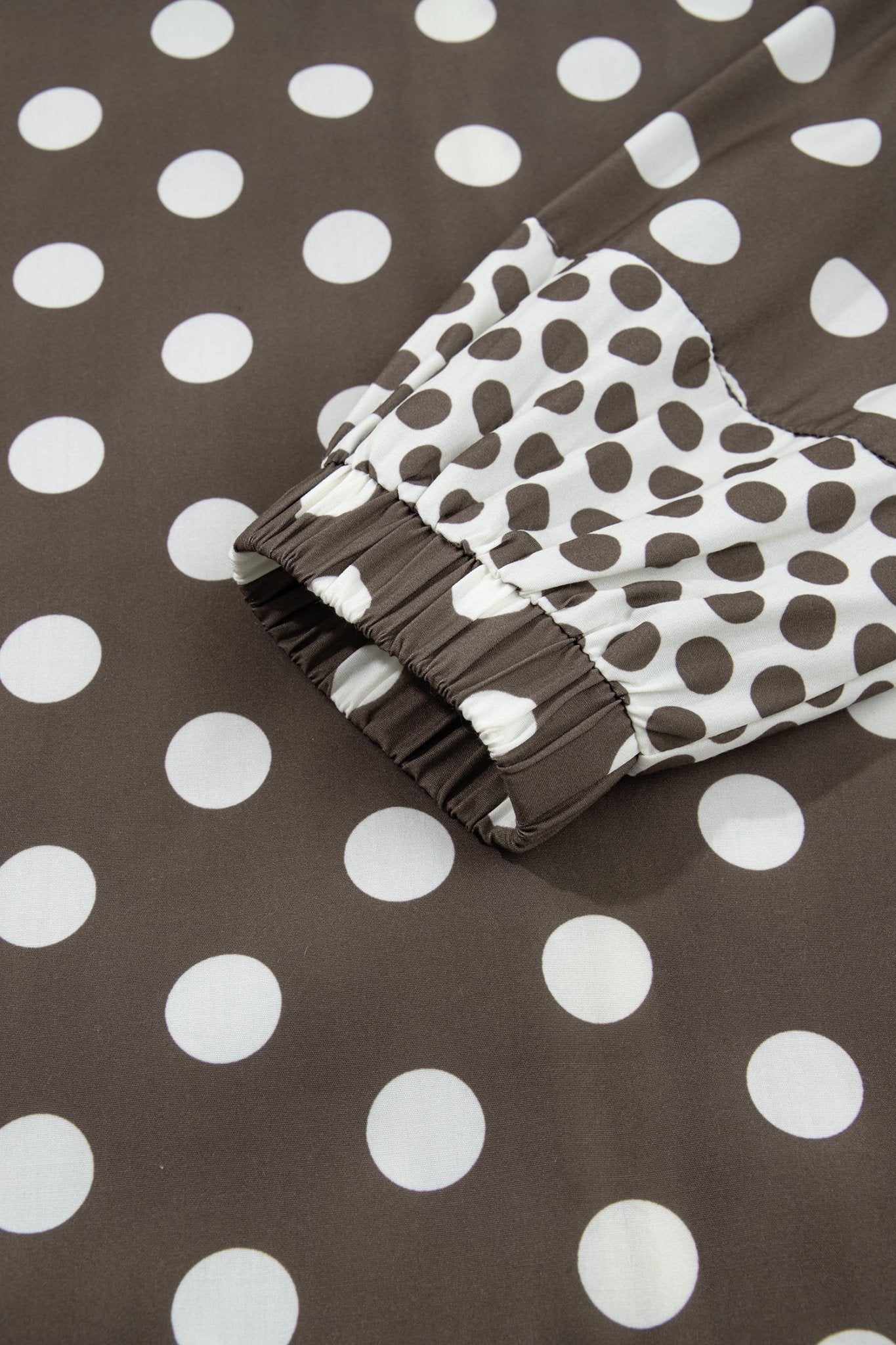 A close-up of a brown and white polka dot garment, showing a ruffled elastic cuff
