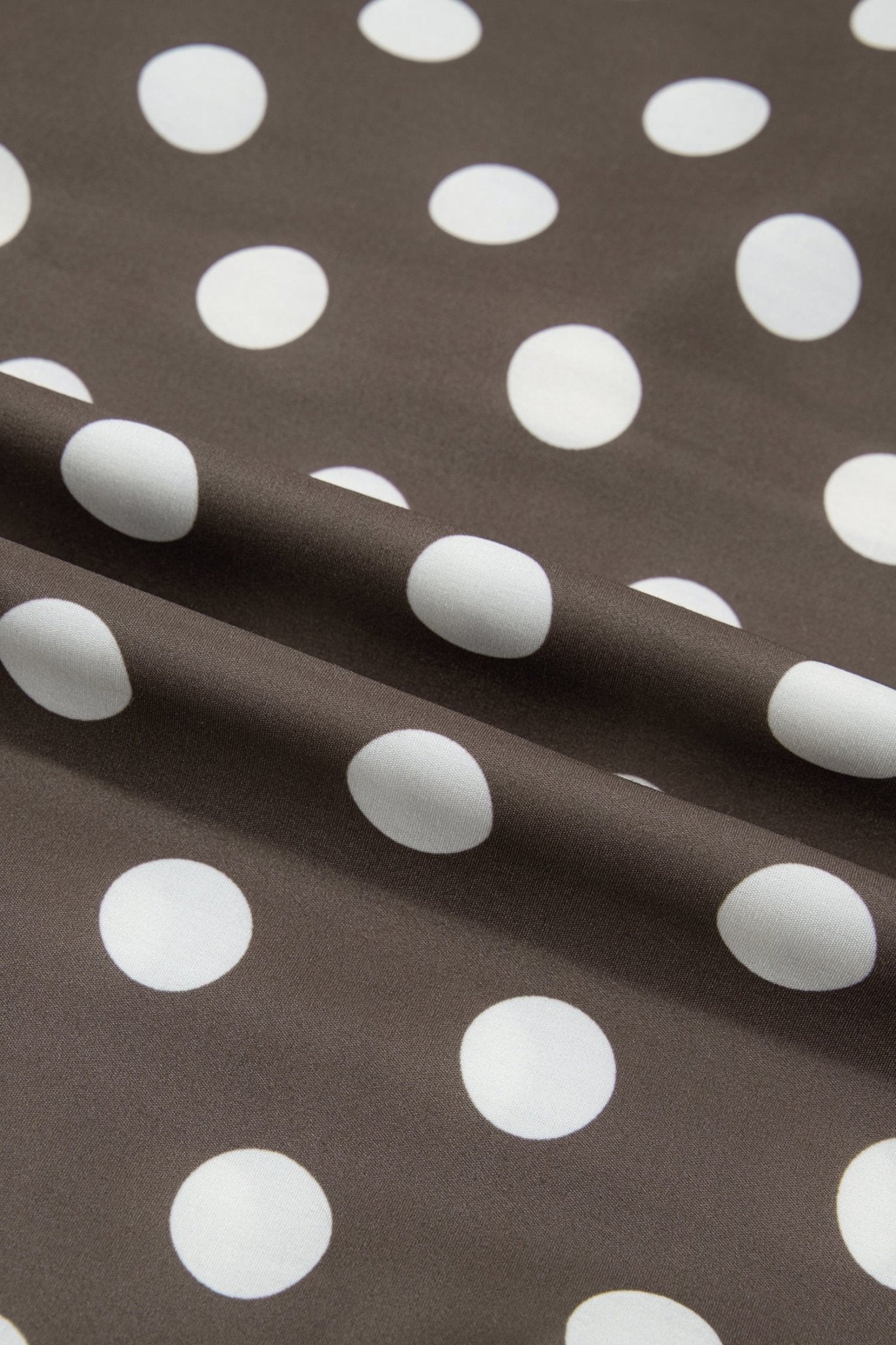 Brown fabric with a white polka dot pattern, draped to show its texture and pattern repeat.