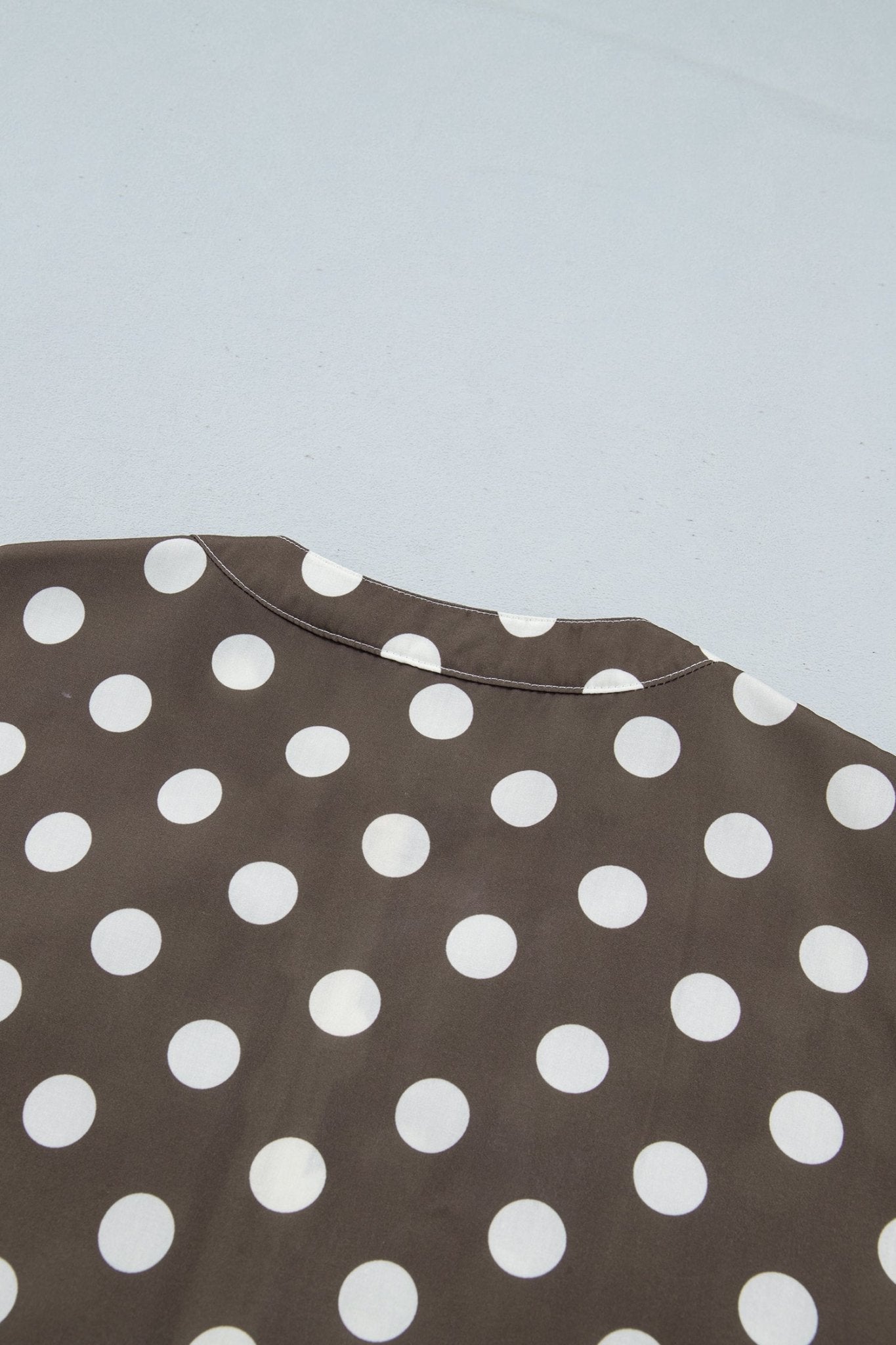 Close-up of a brown garment with a white polka dot pattern, showing the collar