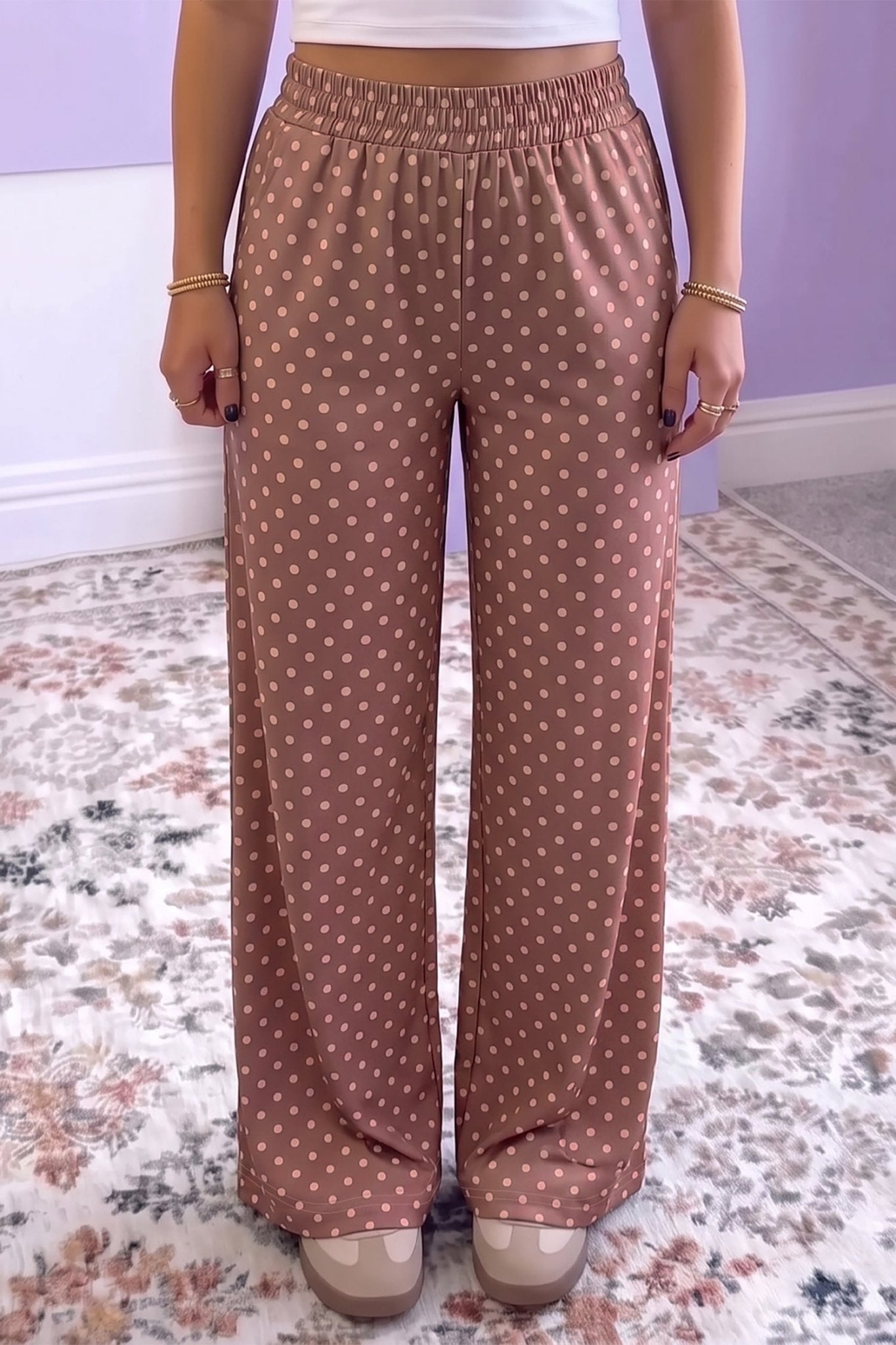 Person in dusty rose-brown polka dot wide-leg pants with white crop top.