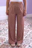 Person in dusty rose-brown polka dot wide-leg pants with white crop top.