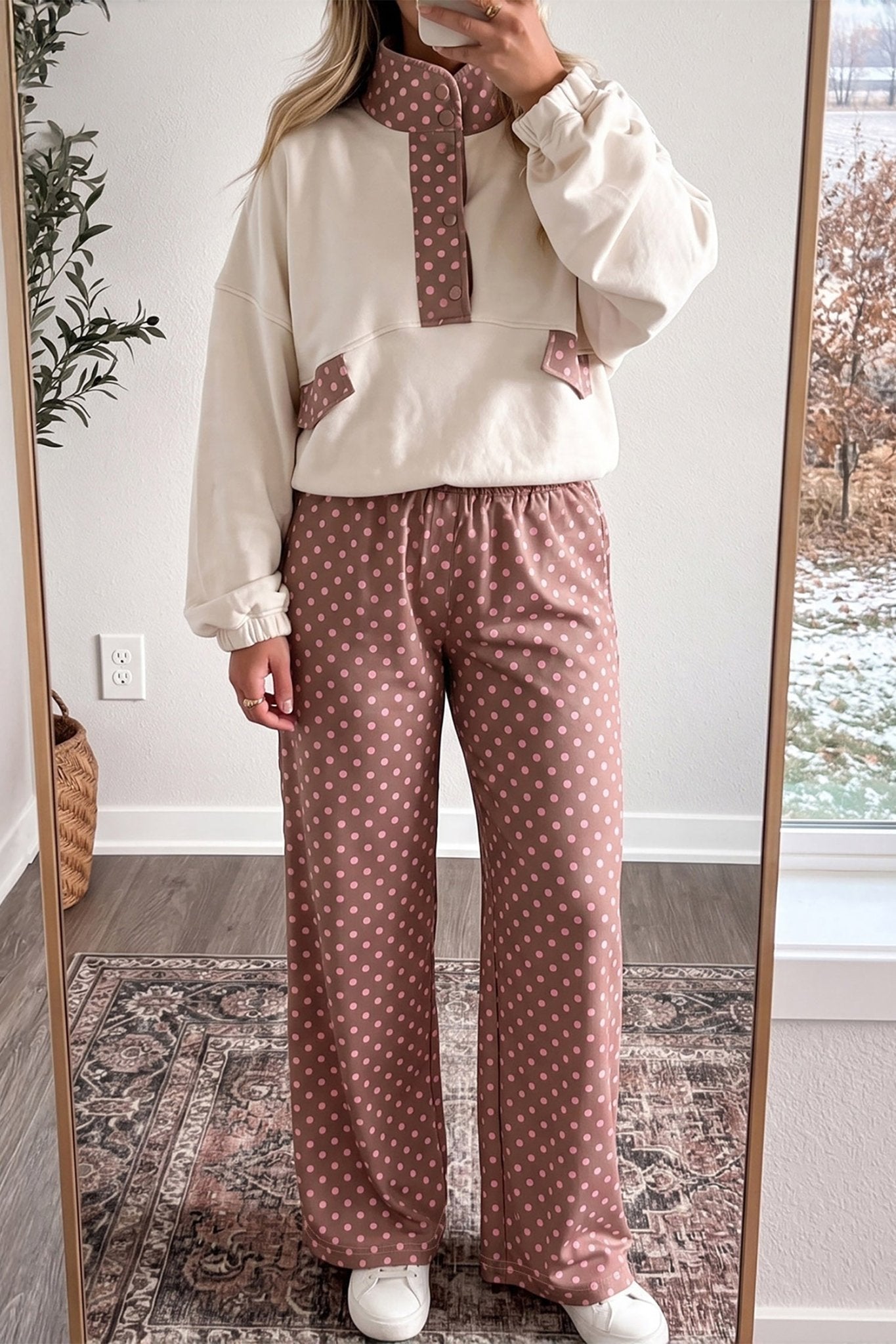 Person in cream sweatshirt with brown polka-dot detail and matching wide-leg pants.
