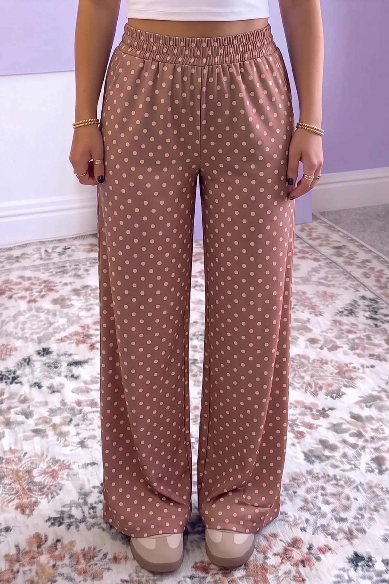 Person in dusty rose-brown polka dot wide-leg pants with white crop top.