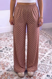 Person in dusty rose-brown polka dot wide-leg pants with white crop top.