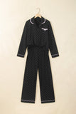 Black polka-dot pajamas with white piping, waist tie, and chest bow on hanger.