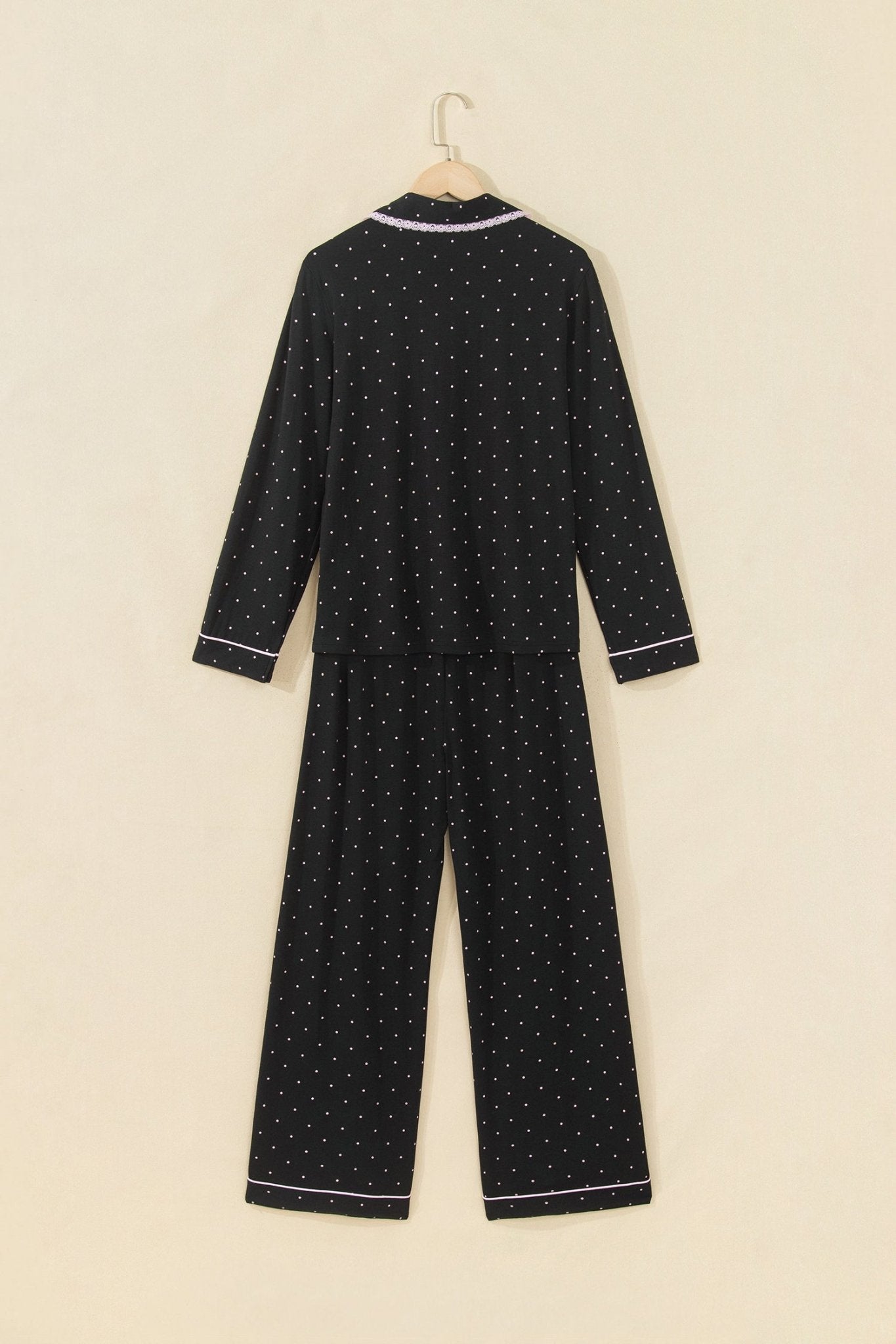 Back view of black polka-dot pajamas with light purple trim on hanger.