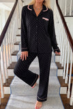 Woman in black polka-dot pajamas with pink trim on indoor staircase.