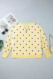 Flat lay of pale yellow blue-dot crewneck sweater with sunglasses, magazine & purse.