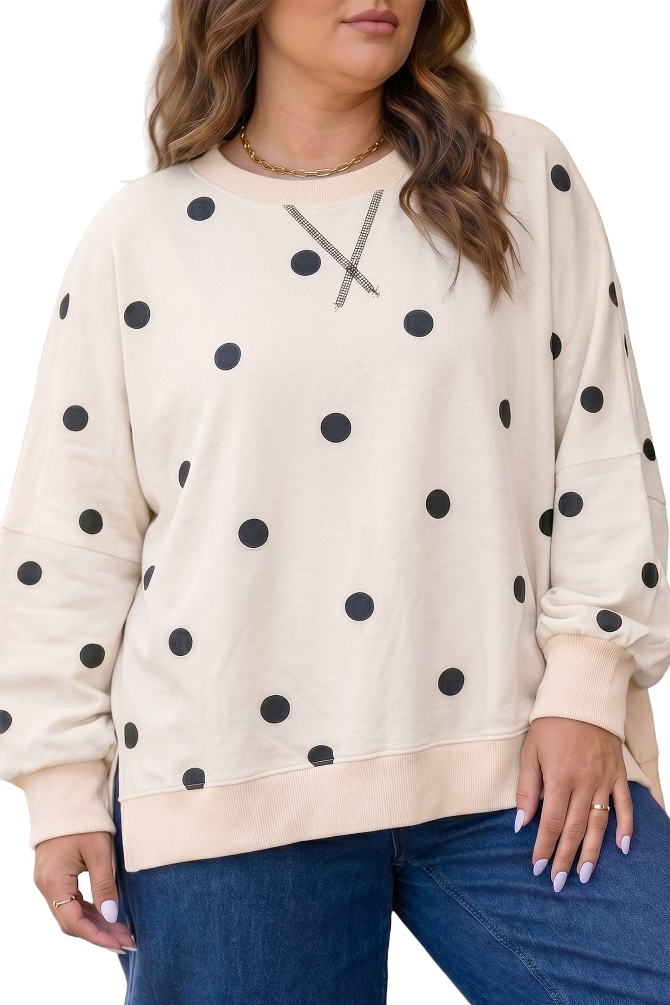 Woman in cream black-polka-dot crewneck with gray chest graphic & jeans.