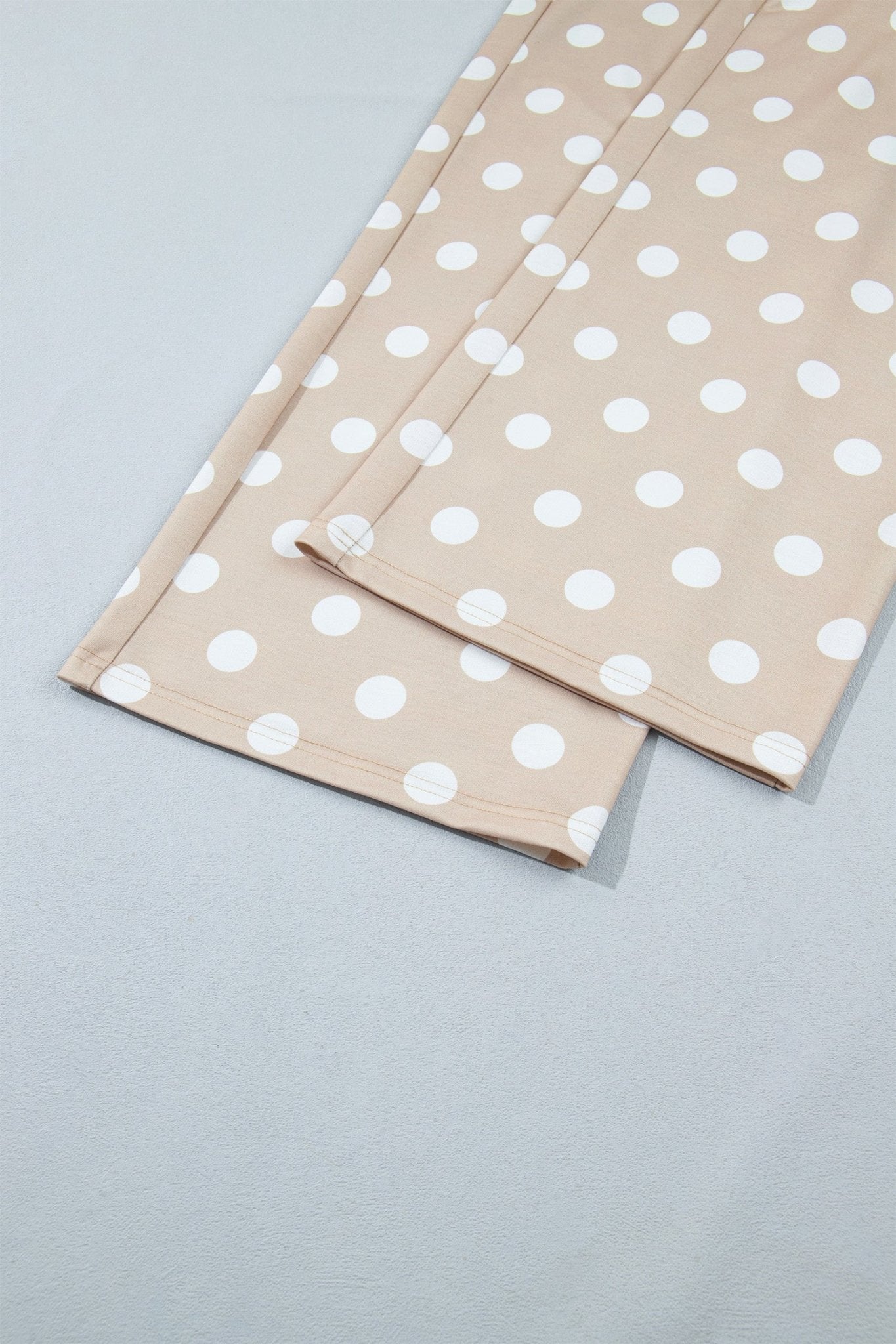 Beige fabric with a white polka dot pattern, folded neatly on a light gray background.