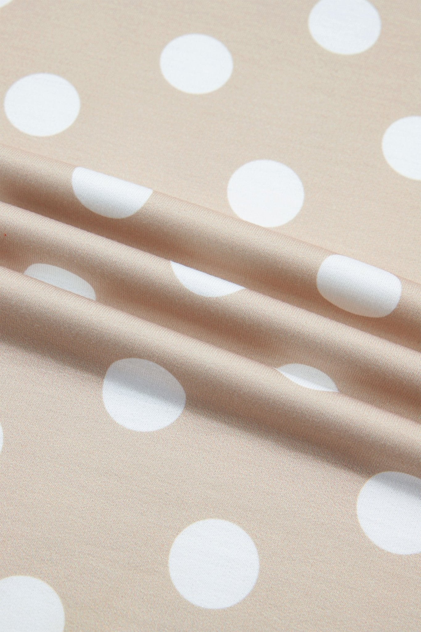 Beige fabric with a white polka dot pattern, draped in soft folds.