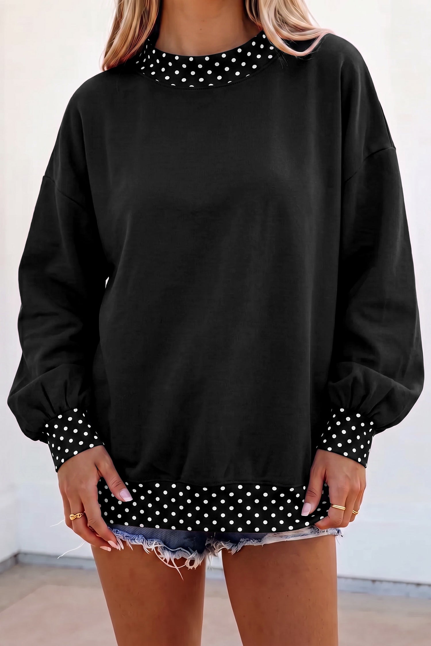 Women's black oversized sweatshirt with cream polka dot trim and balloon sleeves, front view