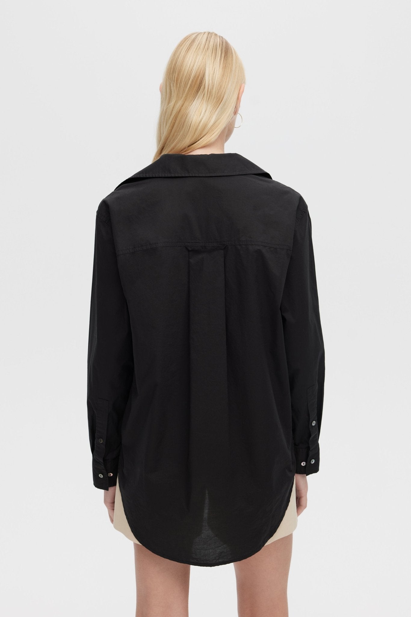 Person wearing a black shirt with a plain background