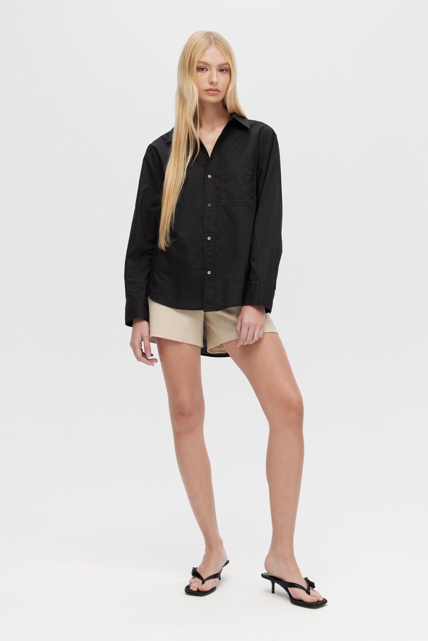 Woman wearing a black shirt and beige shorts on a white background
