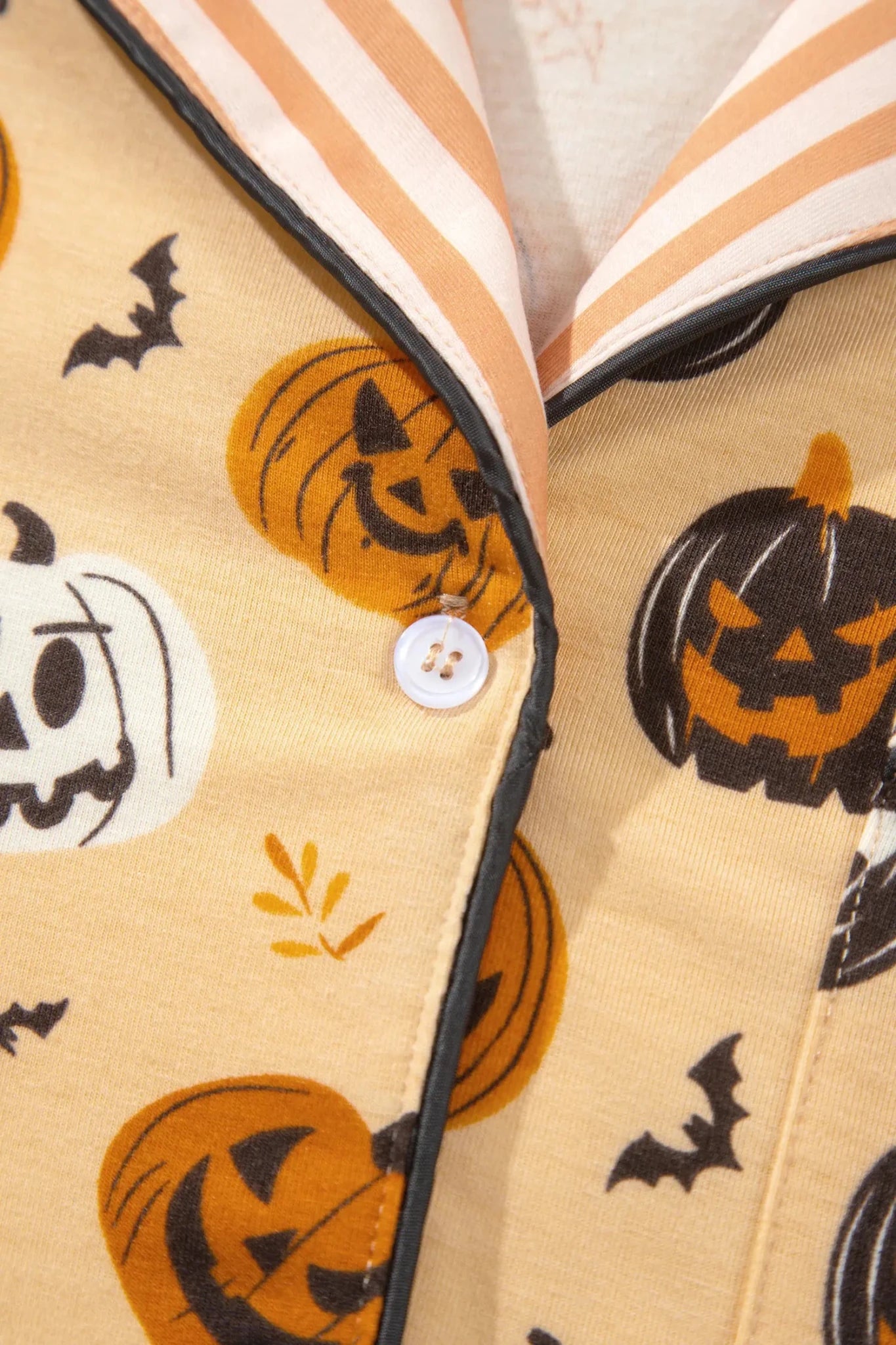 Beige Halloween pajama top with pumpkins, bats, and striped collar.