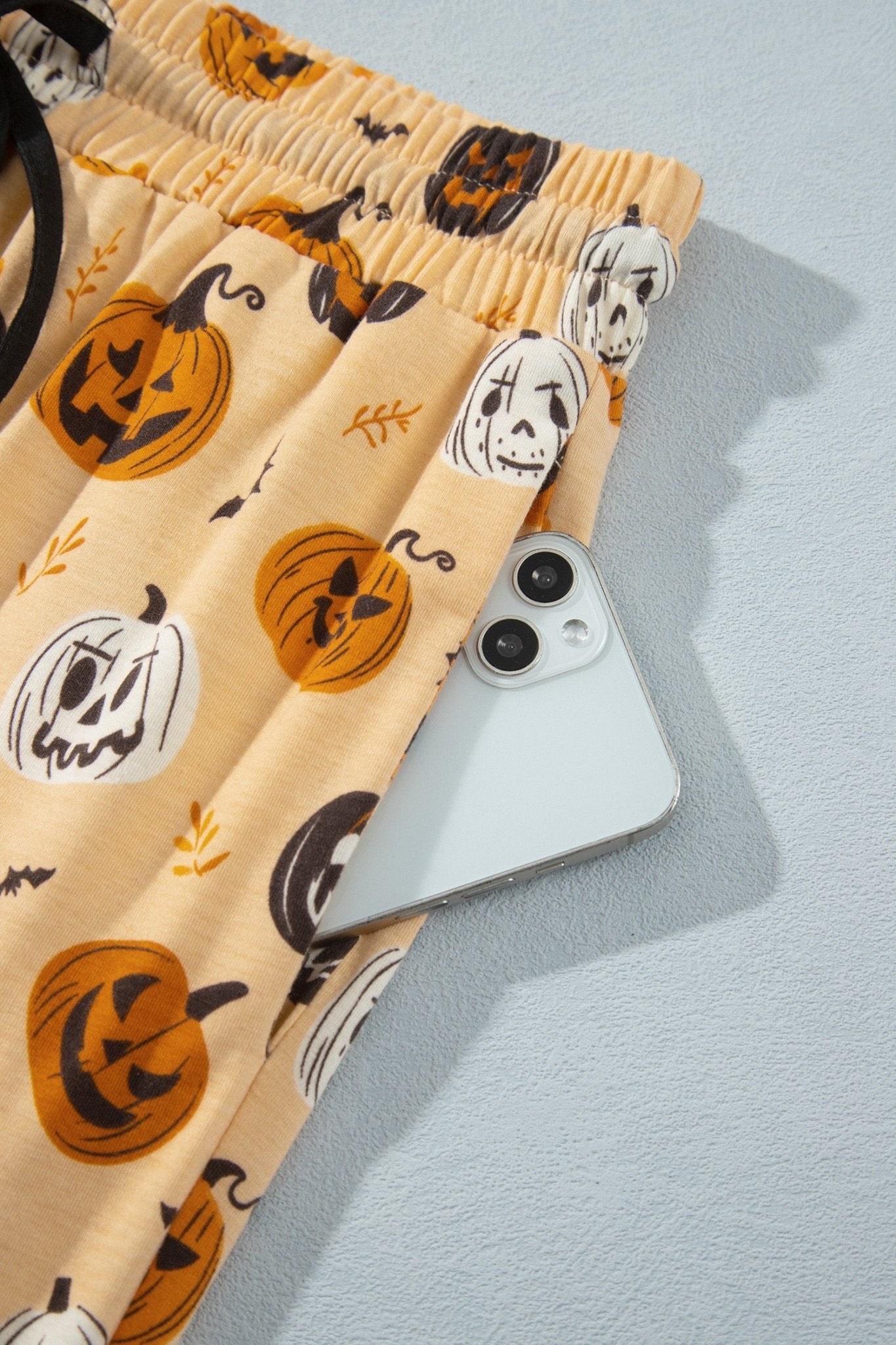 Beige Halloween pajama shorts with jack-o'-lantern, skull, and bat prints.
