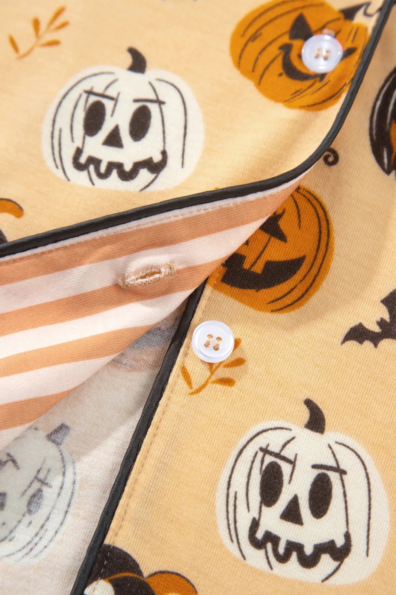 Cream Halloween pajama top with pumpkins, bats, leaves, and stripes.