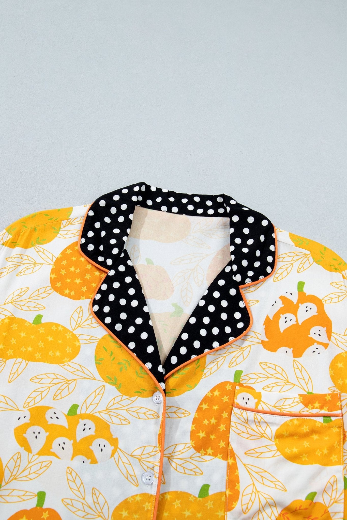 Close-up of white pumpkin-print pajama top with black polka-dot collar.