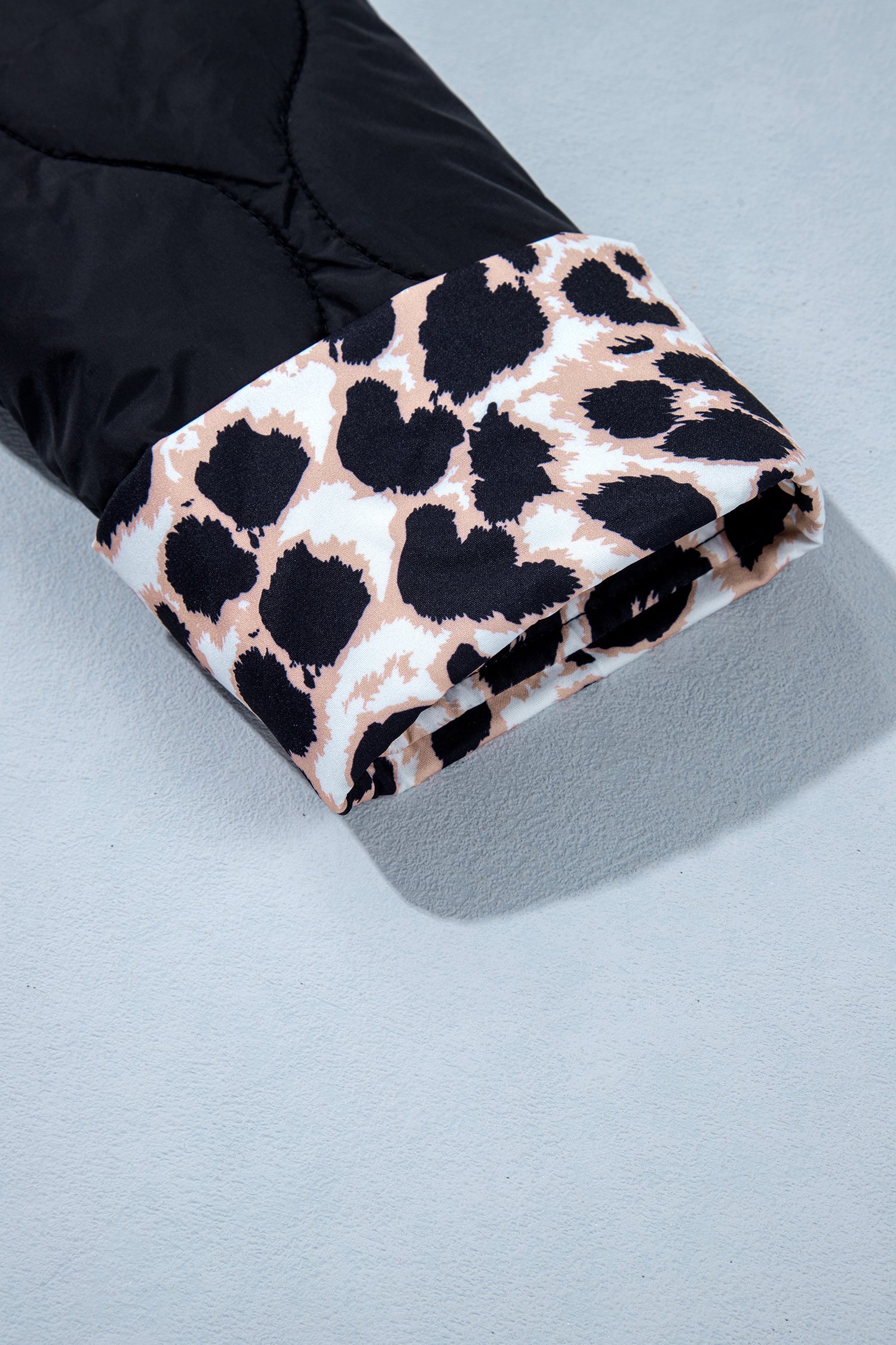 Turned-back leopard print cuff on black quilted sleeve