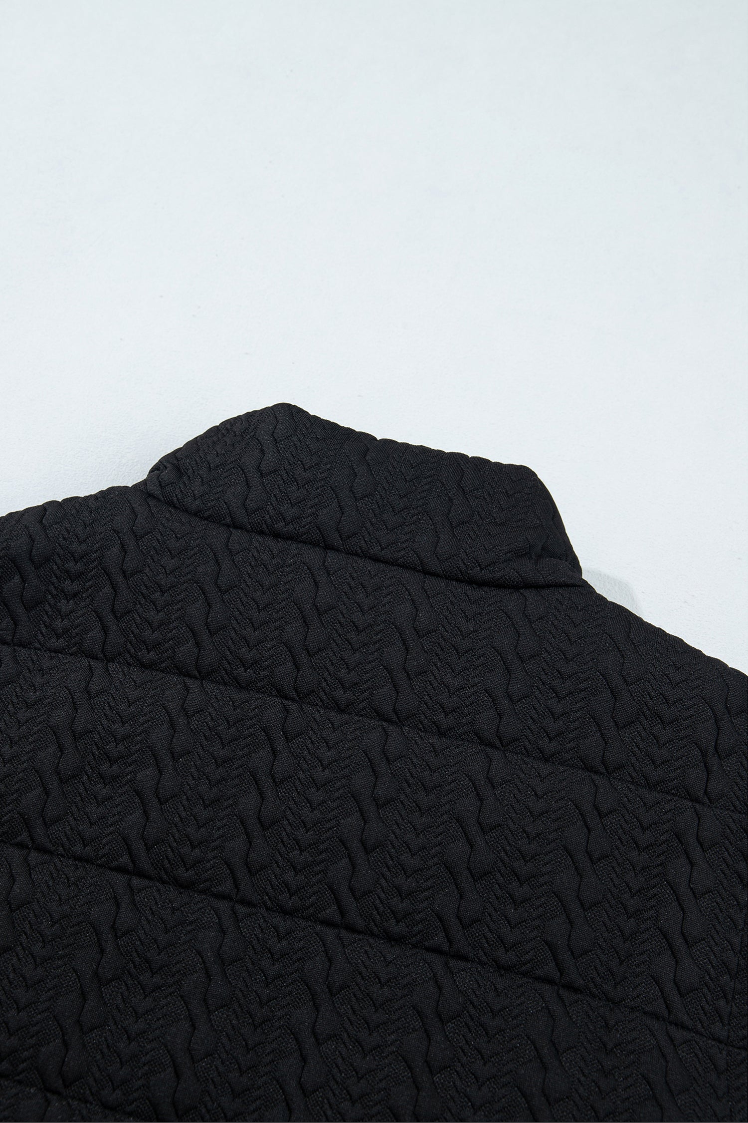 Black quilted vest back collar and cable texture detail