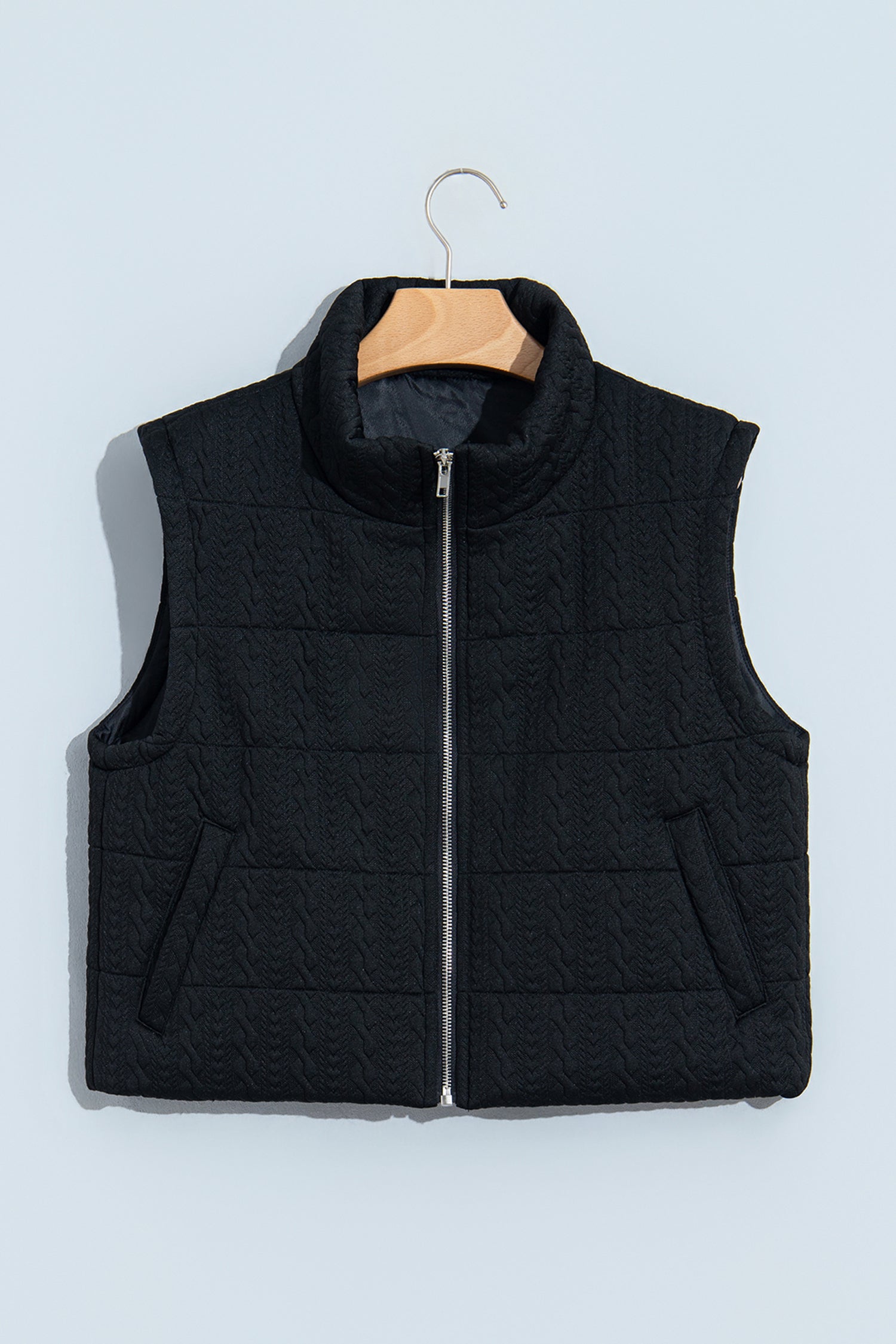 Black quilted zip up vest with stand collar on a hanger, front view