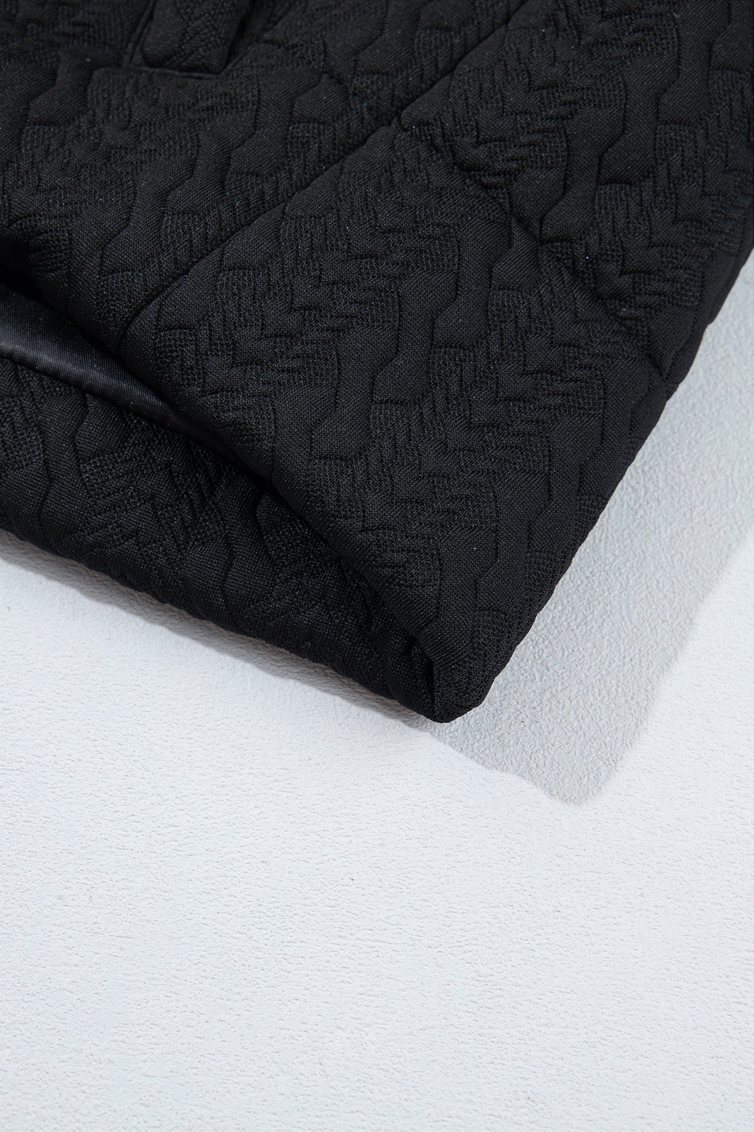 Black quilted vest hem and cable texture detail