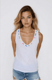 Woman wearing a white tank top with colorful accents against a plain background