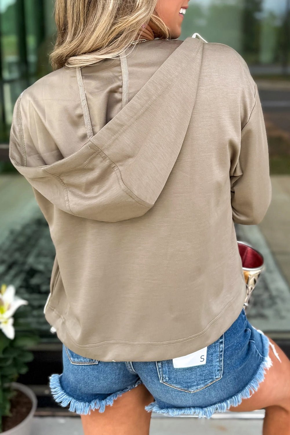 Person wearing a beige hoodie and denim shorts outdoors