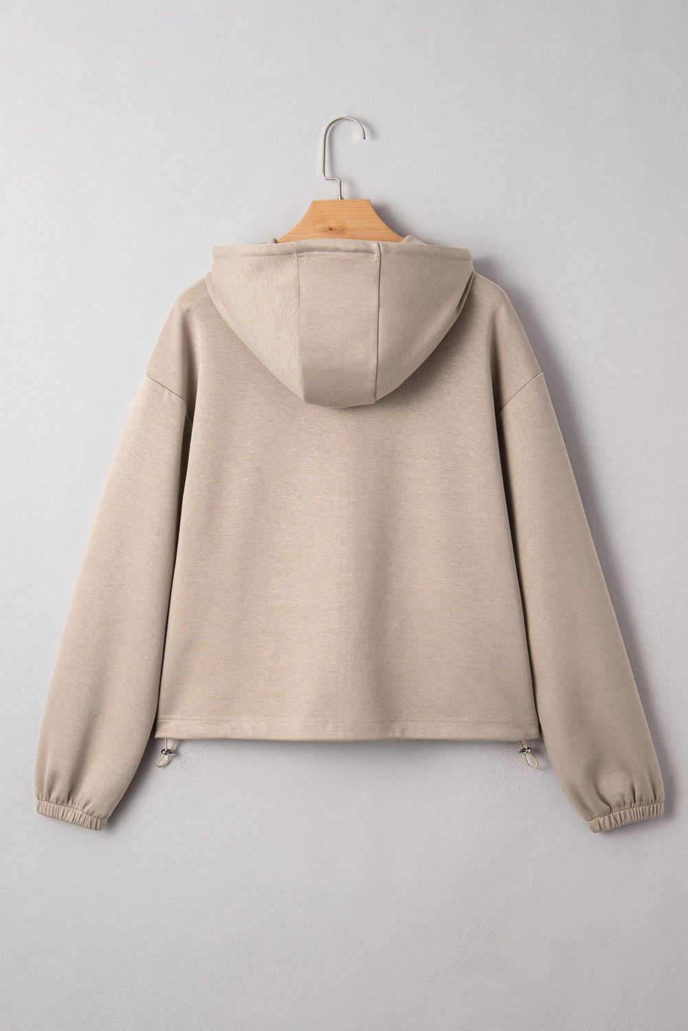 Beige hoodie on a wooden hanger against a gray background
