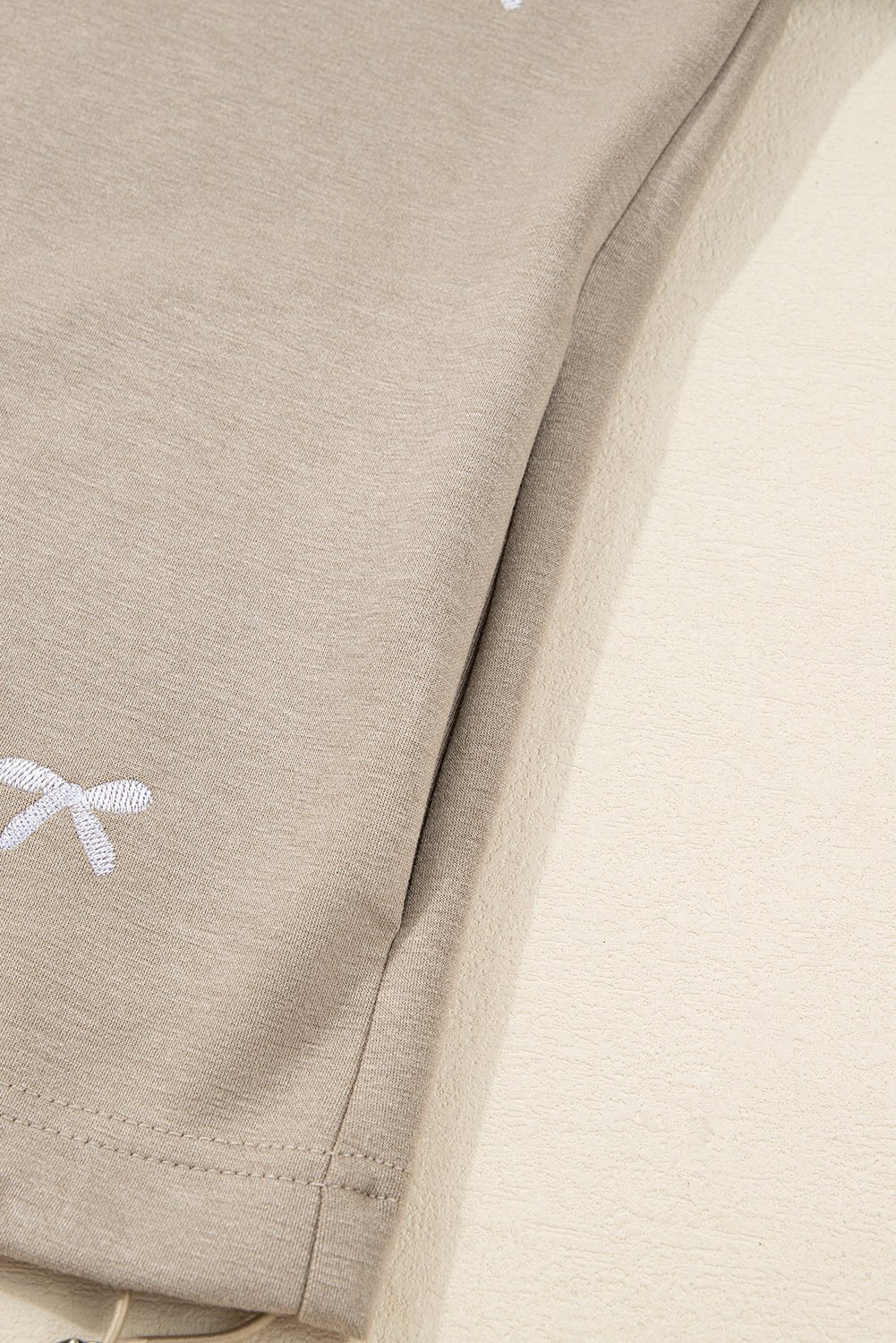Close-up of beige fabric with a small white logo on a beige background