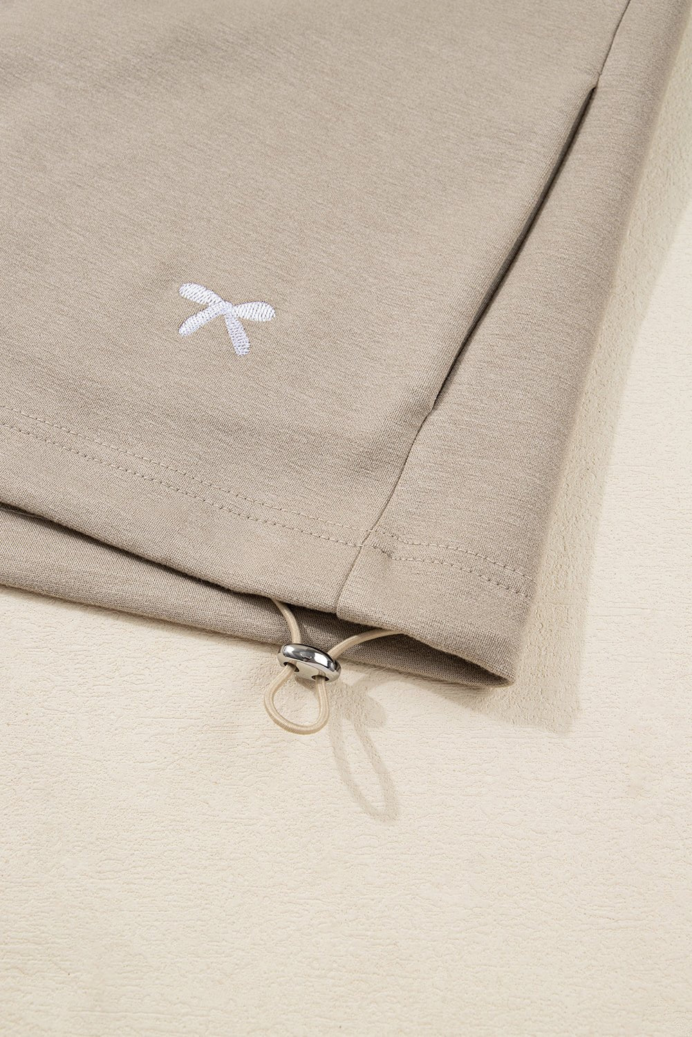 Close-up of beige fabric with a small white logo on a beige background