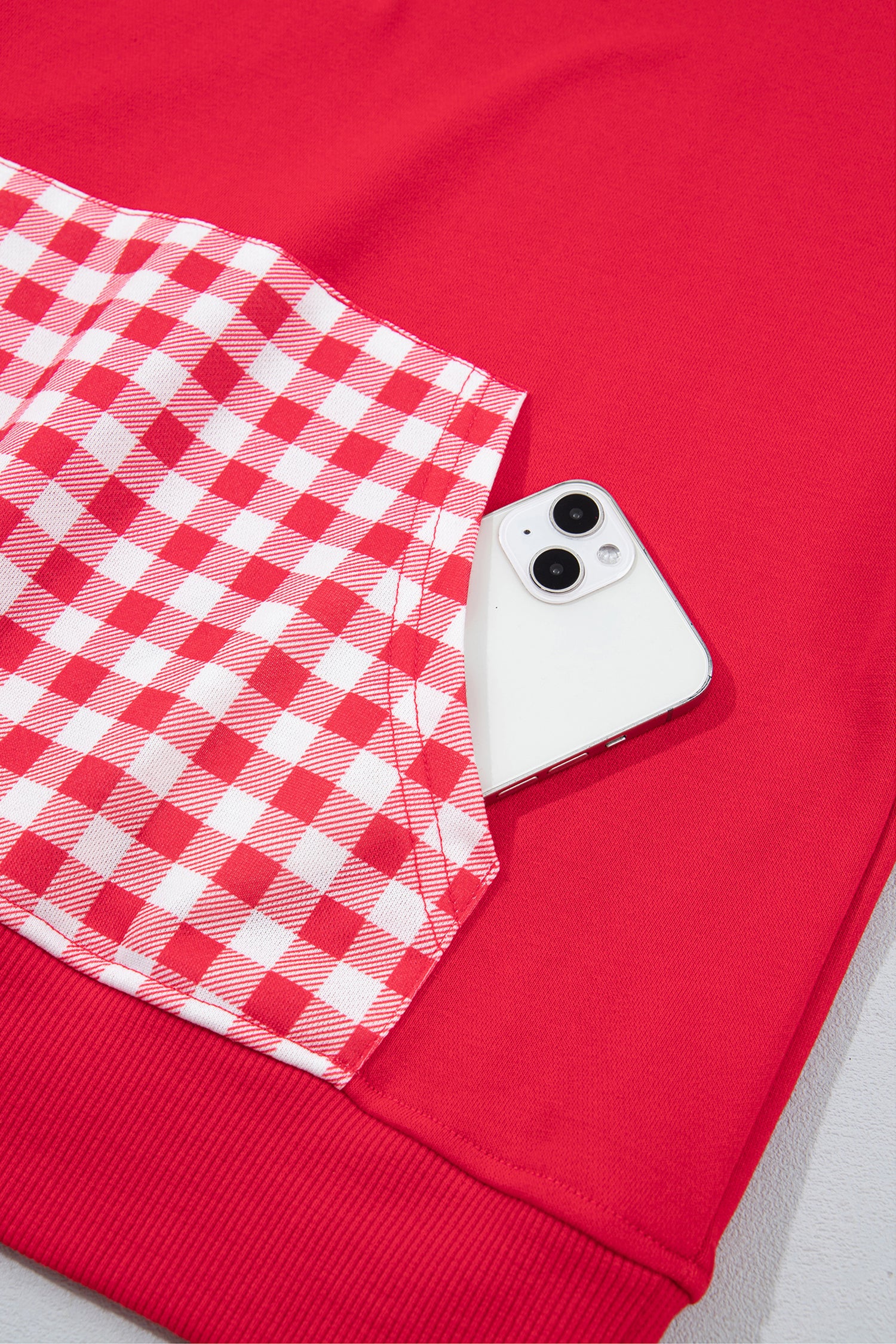 Racing red sweatshirt gingham kangaroo pocket holding a phone