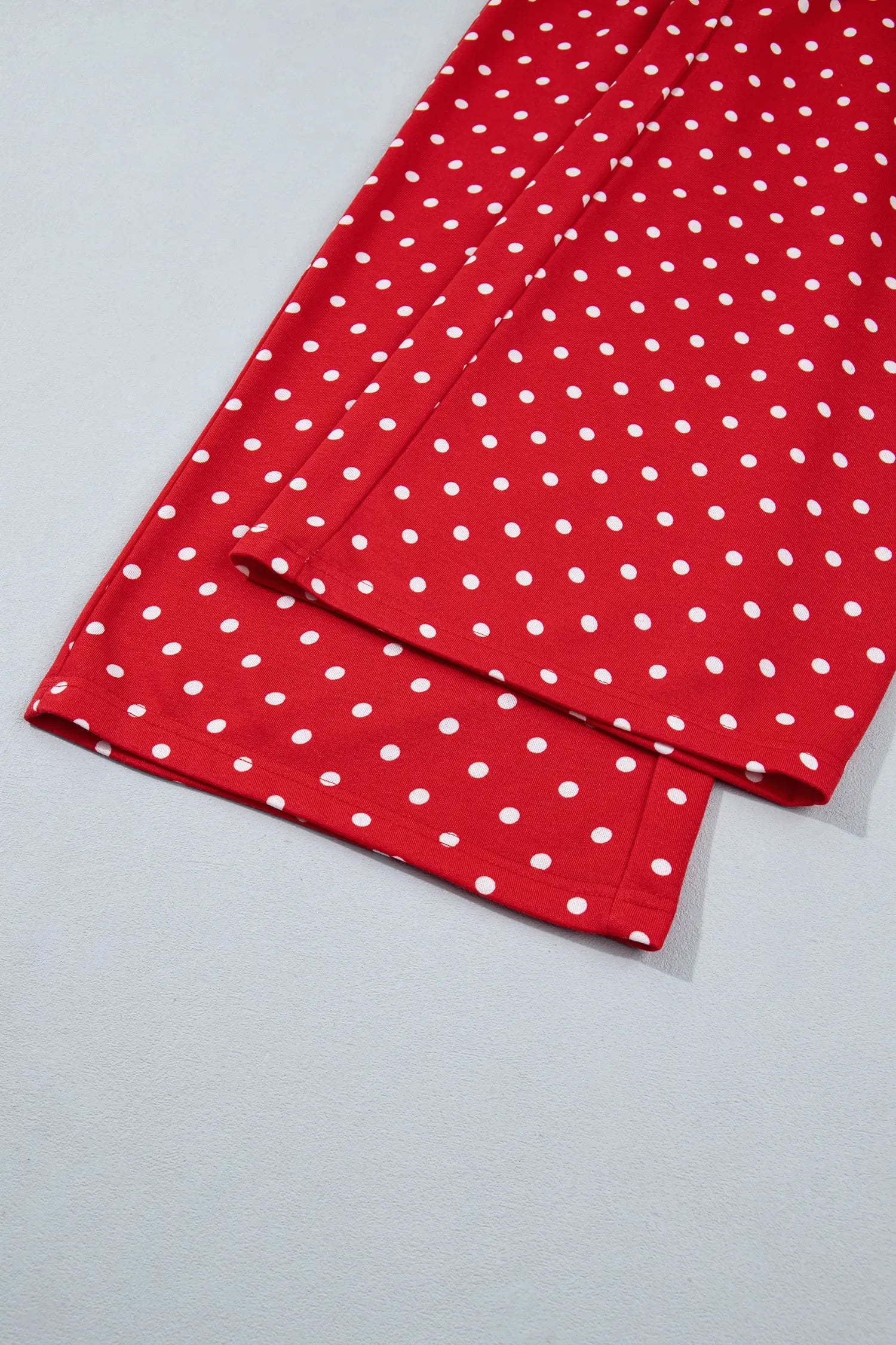 Wide leg hem of the red polka dot pants laid flat